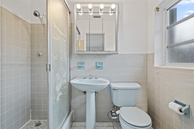 bathroom featuring tile patterned flooring, sink, tile walls, and toilet