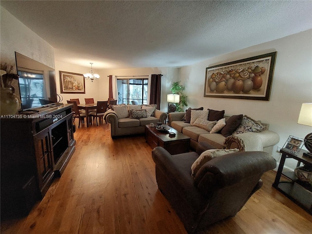 living room with an inviting chandelier, a textured ceiling, and light hardwood / wood-style flooring