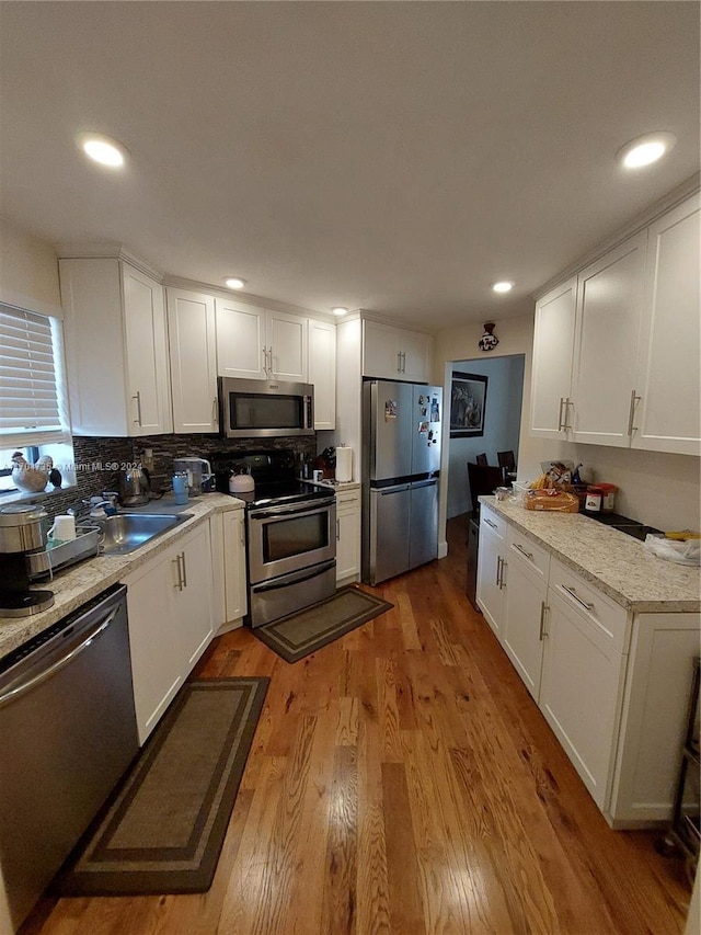 kitchen with stainless steel appliances, light hardwood / wood-style flooring, and white cabinetry