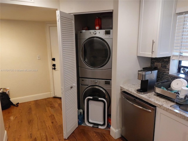 laundry room featuring light hardwood / wood-style flooring and stacked washer and clothes dryer