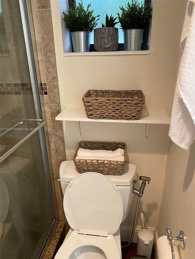 bathroom with toilet and a shower with door