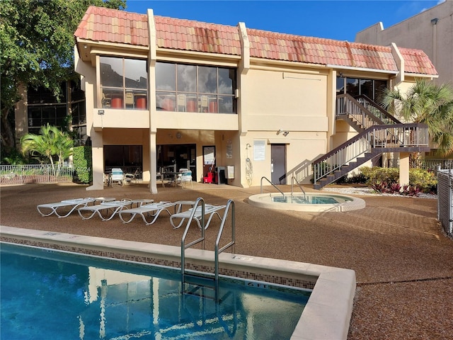 back of property featuring a patio area and a swimming pool with hot tub