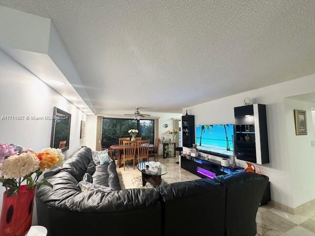 living room with ceiling fan and a textured ceiling