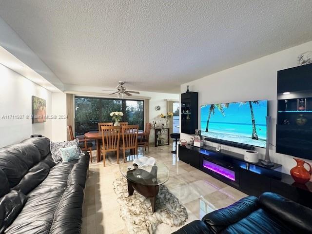 living room with ceiling fan and a textured ceiling