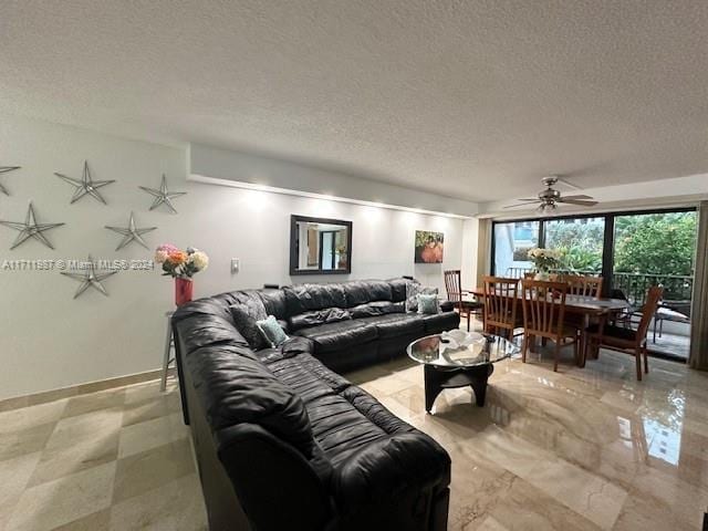 living room featuring ceiling fan and a textured ceiling