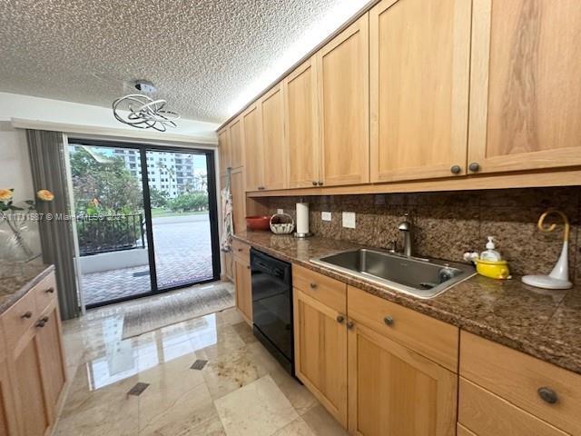 kitchen featuring dishwasher, dark stone counters, a textured ceiling, and sink