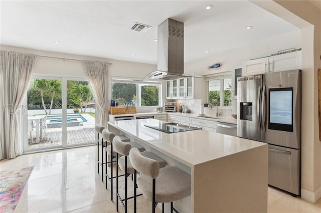 kitchen with island range hood, sink, white cabinets, and stainless steel appliances