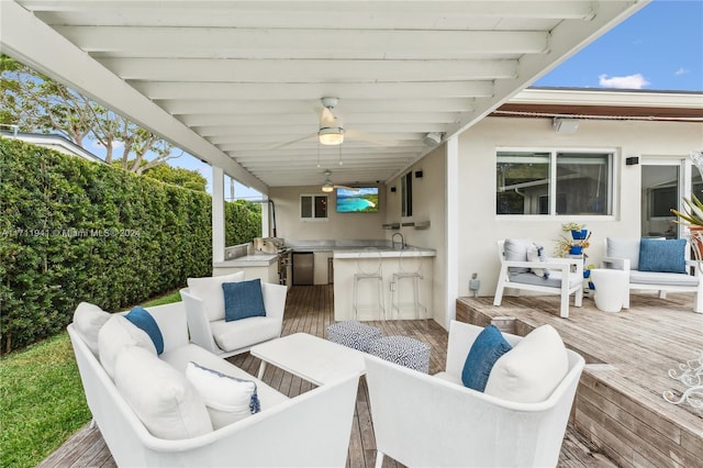 view of patio / terrace featuring ceiling fan, exterior kitchen, sink, and a wooden deck