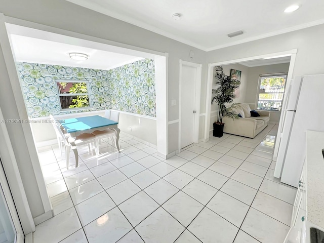 hall featuring light tile patterned floors and crown molding