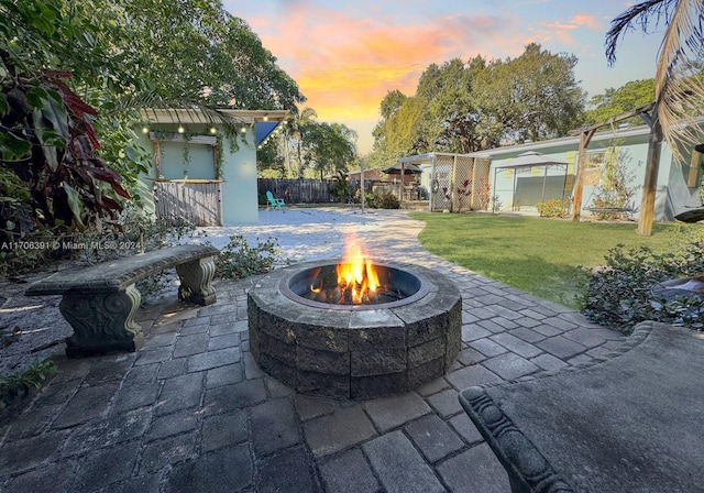 patio terrace at dusk with a fire pit and a lawn