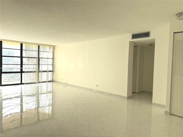 empty room with a textured ceiling and expansive windows