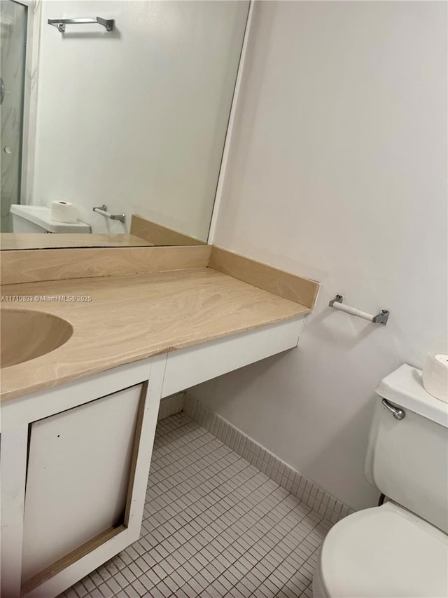 bathroom with toilet, vanity, and tile patterned floors