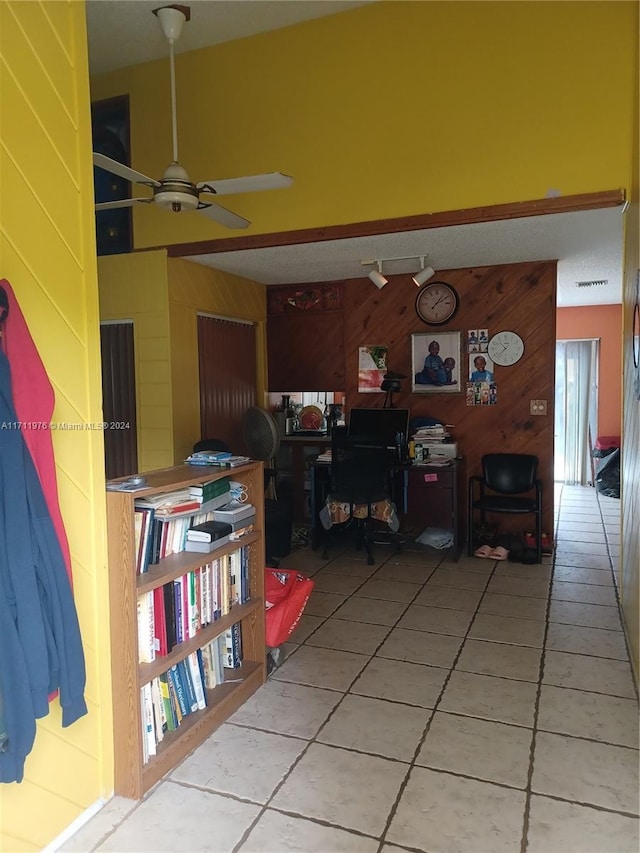 interior space with tile patterned flooring, ceiling fan, and wooden walls