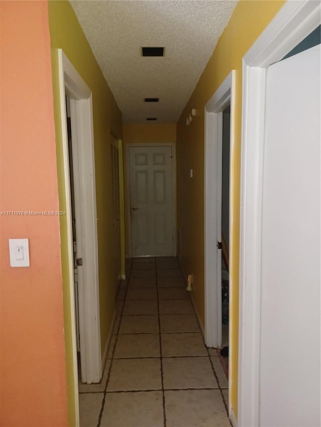 corridor featuring light tile patterned floors and a textured ceiling