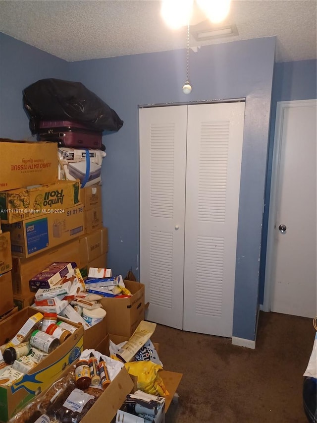 bedroom featuring dark colored carpet, a textured ceiling, and a closet