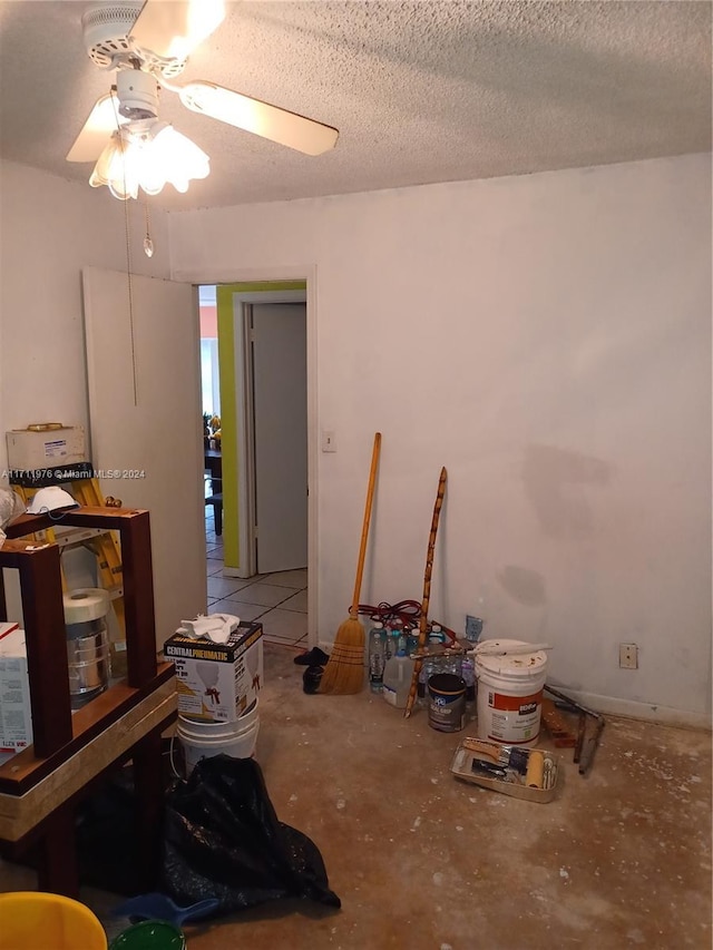 miscellaneous room with ceiling fan and a textured ceiling