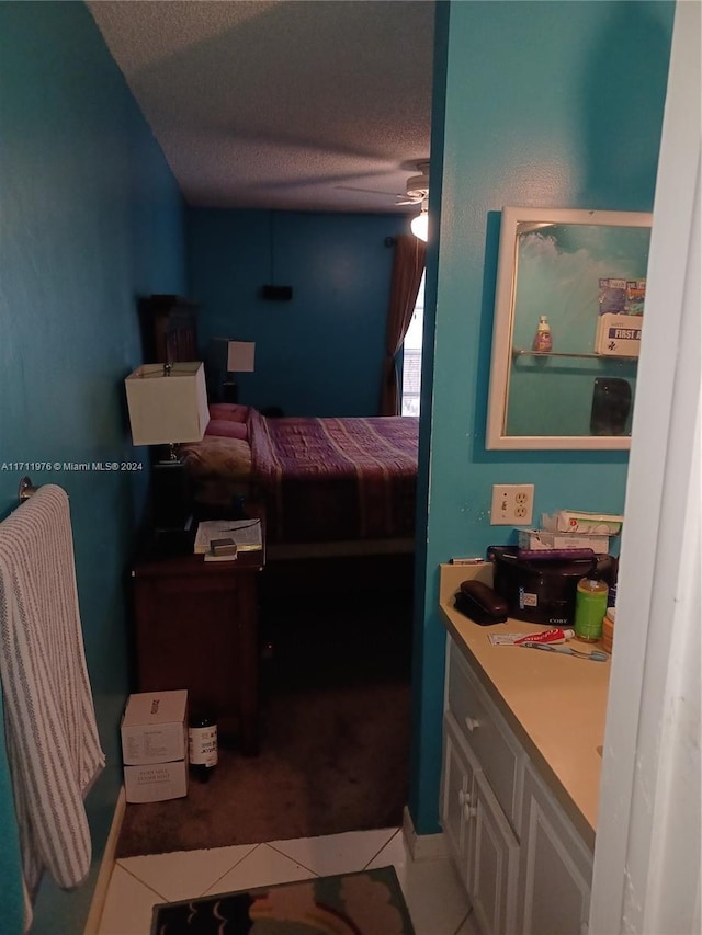 bedroom with ceiling fan, tile patterned flooring, and a textured ceiling