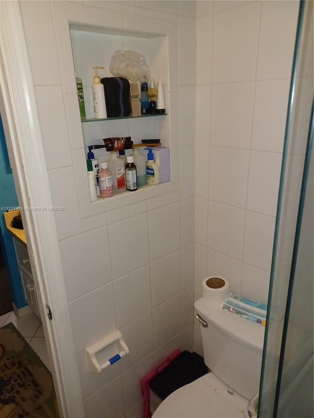 bathroom with tile patterned floors, toilet, and tile walls