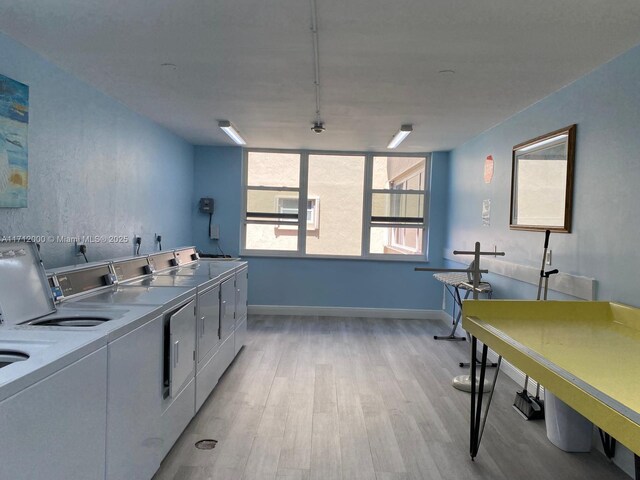community laundry room featuring baseboards, light wood finished floors, and washer and clothes dryer