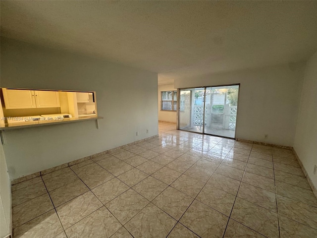 spare room with a textured ceiling and light tile patterned flooring