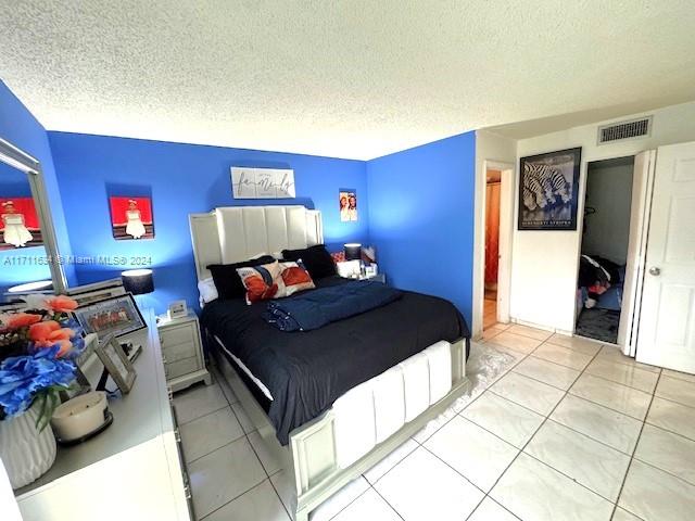 bedroom with light tile patterned floors and a textured ceiling