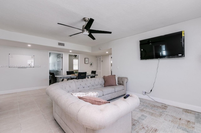 living room featuring ceiling fan, light tile patterned flooring, and a textured ceiling