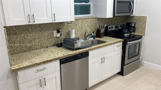 kitchen with white cabinets, light tile patterned floors, tasteful backsplash, light stone counters, and stainless steel appliances