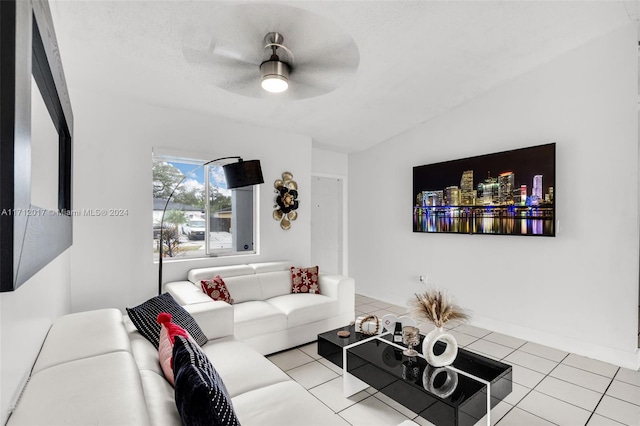 living room featuring ceiling fan, light tile patterned flooring, lofted ceiling, and a textured ceiling