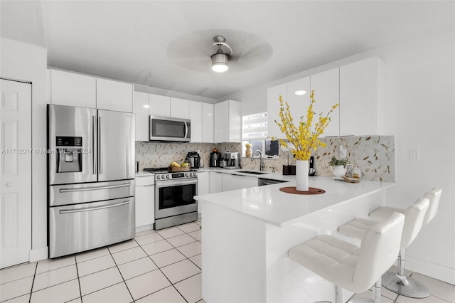 kitchen with white cabinetry, sink, a kitchen breakfast bar, kitchen peninsula, and appliances with stainless steel finishes