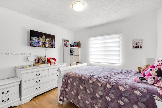 bedroom featuring a textured ceiling and light hardwood / wood-style flooring