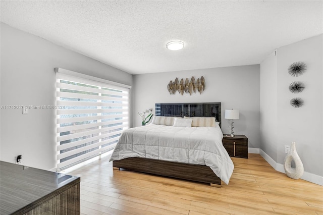 bedroom with a textured ceiling and light hardwood / wood-style floors