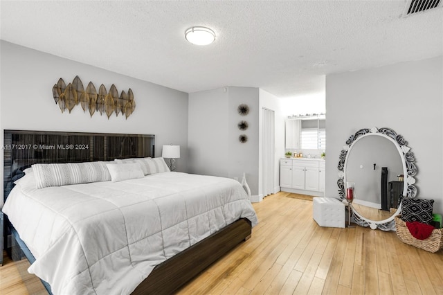 bedroom featuring wood-type flooring, connected bathroom, and a textured ceiling