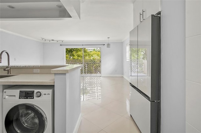 clothes washing area featuring sink, washer / dryer, light tile patterned floors, and crown molding