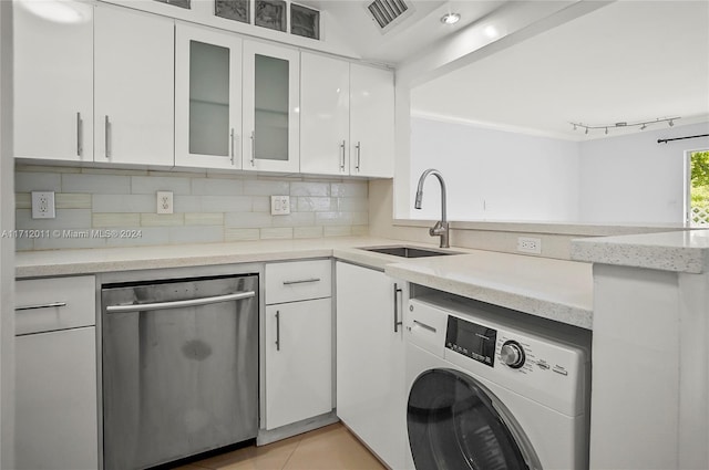 kitchen with dishwasher, sink, light tile patterned floors, washer / dryer, and white cabinetry