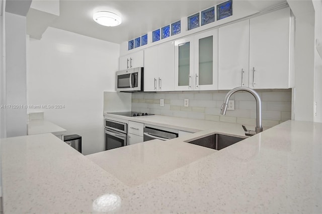 kitchen with decorative backsplash, sink, white cabinetry, and stainless steel appliances