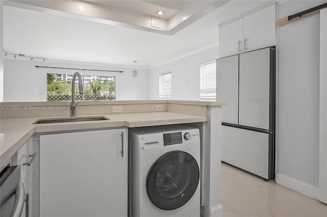 clothes washing area with crown molding, sink, light tile patterned floors, a barn door, and washer / clothes dryer