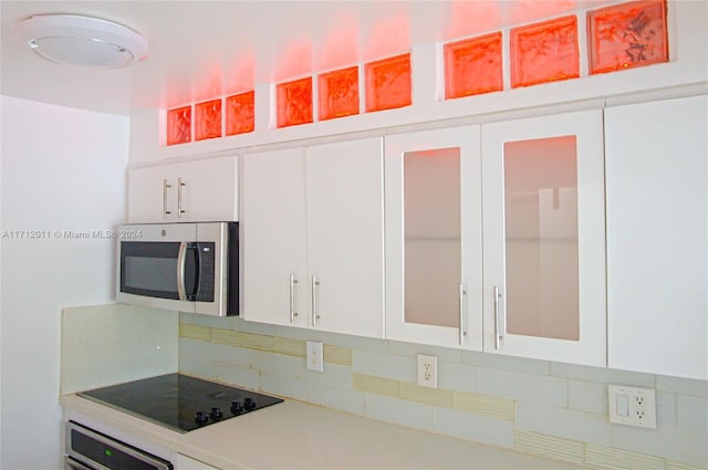 kitchen with white cabinets, wall oven, black electric stovetop, and backsplash