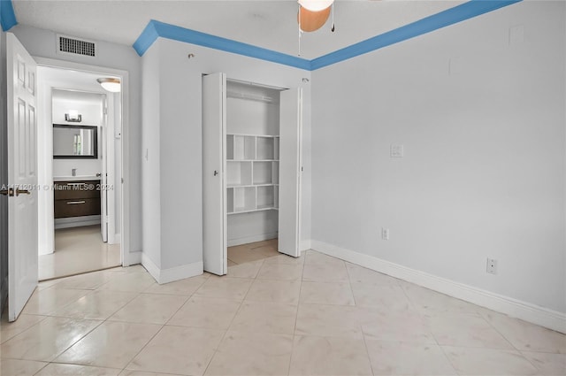 unfurnished bedroom with ceiling fan, light tile patterned floors, and a closet