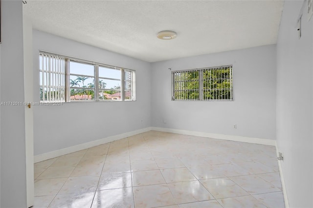 unfurnished room with light tile patterned floors and a textured ceiling