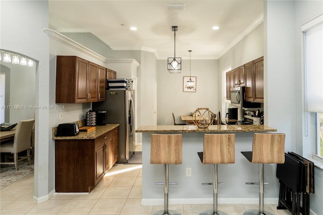 kitchen featuring a kitchen bar, dark stone countertops, crown molding, and kitchen peninsula