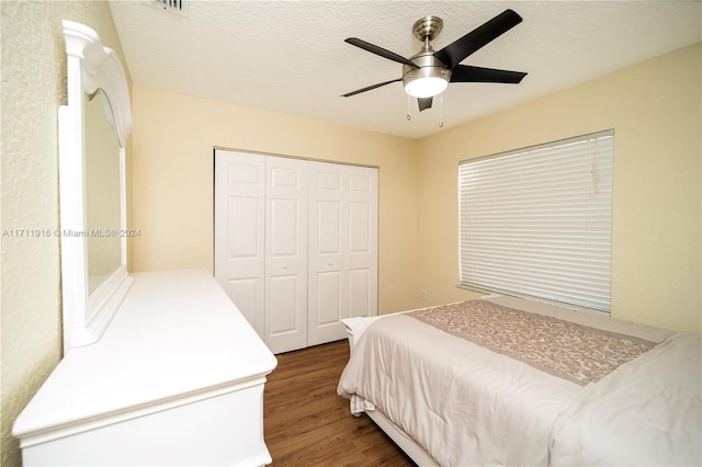 bedroom featuring a textured ceiling, dark hardwood / wood-style flooring, a closet, and ceiling fan