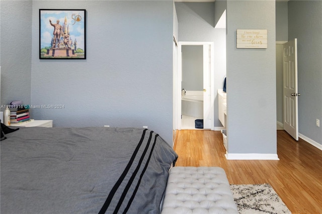 bedroom with ensuite bathroom and light hardwood / wood-style floors