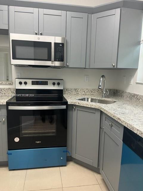 kitchen featuring gray cabinetry, sink, stainless steel appliances, light stone counters, and light tile patterned flooring