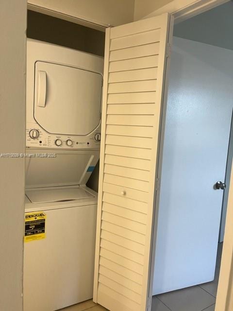 laundry room featuring tile patterned flooring and stacked washing maching and dryer