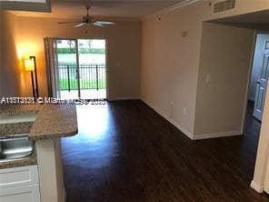 unfurnished living room featuring baseboards, visible vents, a ceiling fan, dark wood-type flooring, and crown molding