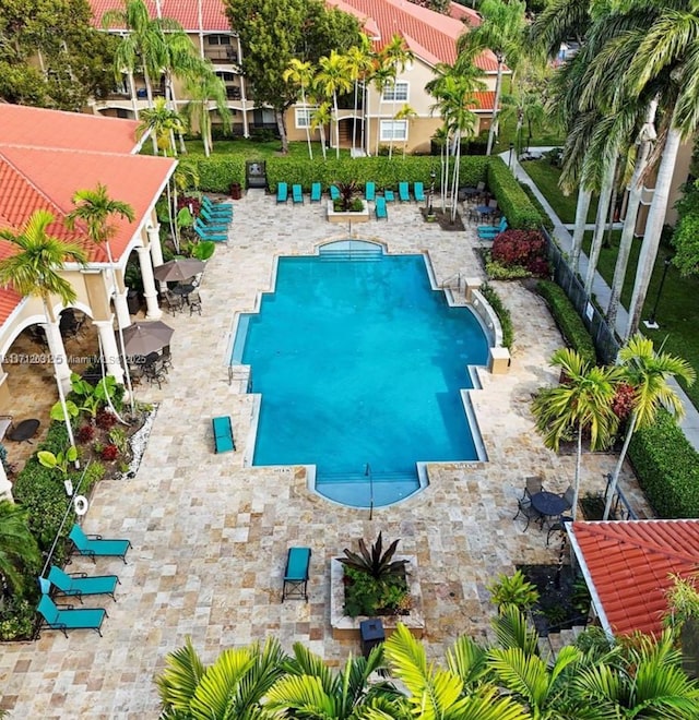 community pool with a patio area and fence