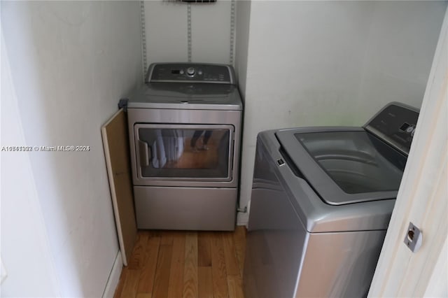 laundry room with washer and clothes dryer and light wood-type flooring