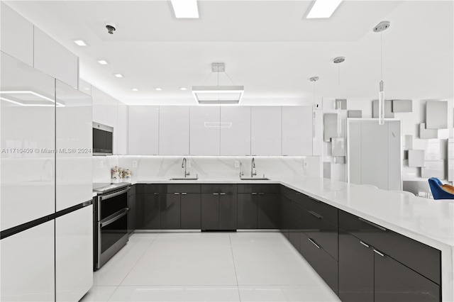 kitchen with sink, white cabinets, hanging light fixtures, and appliances with stainless steel finishes