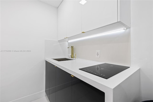 kitchen with white cabinetry, sink, and black electric cooktop