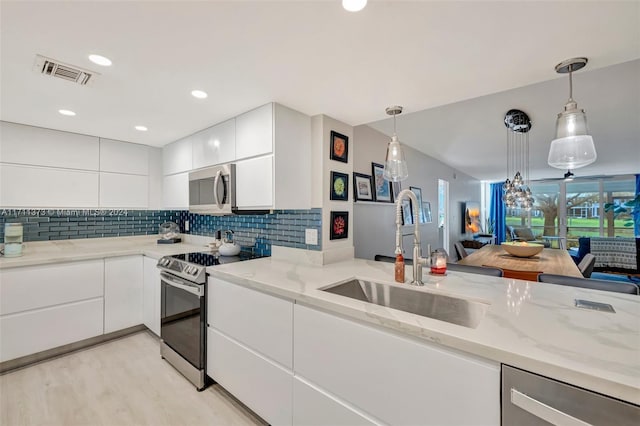 kitchen featuring hanging light fixtures, white cabinets, stainless steel appliances, and sink